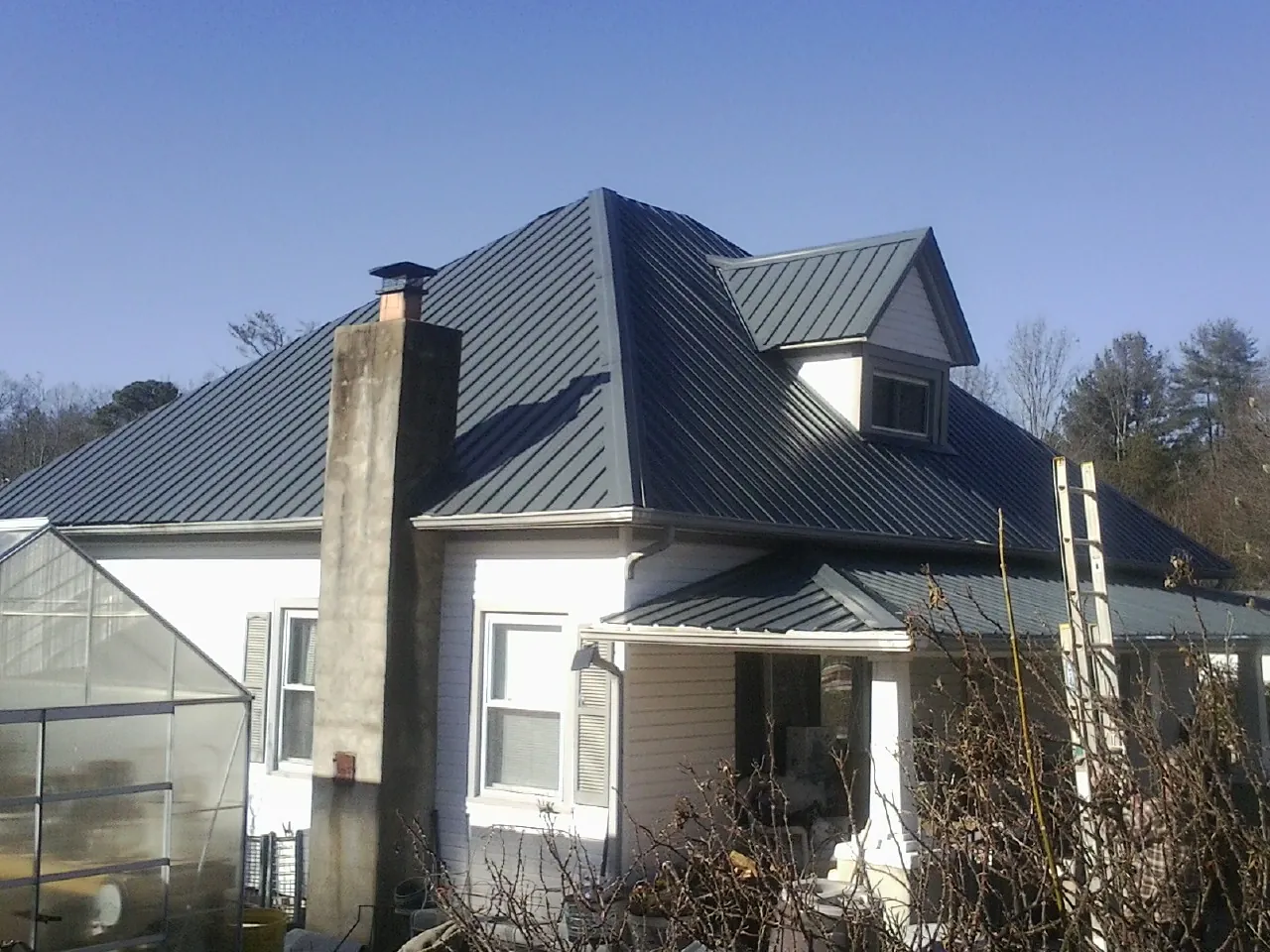 Dark blue standing seam metal roof on a white farmhouse with dormer — Slate & Tile Roof Repair by Roofing Brothers in Sutherland
