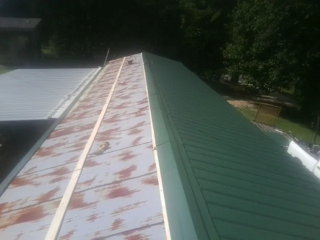Old rusted panels beside newly installed green metal roofing — Wind Damage Roof Repair by Roofing Brothers in Sutherland