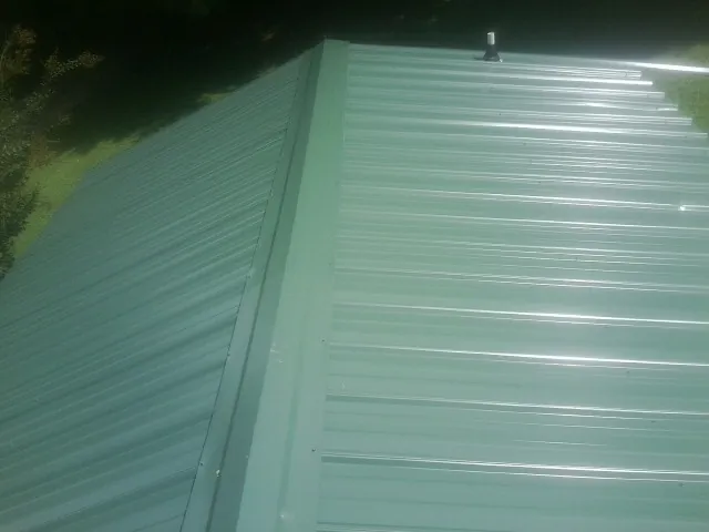 New green metal panels meeting at the ridge of a roof — Flat Roof Repair work by our crew in Sutherland